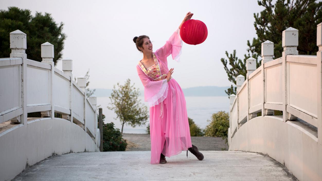 A person in a pink dress posing with a red moon ornament
