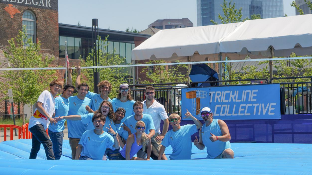A group of people wearing blue shirts in front of a sign that says Trickline Collective
