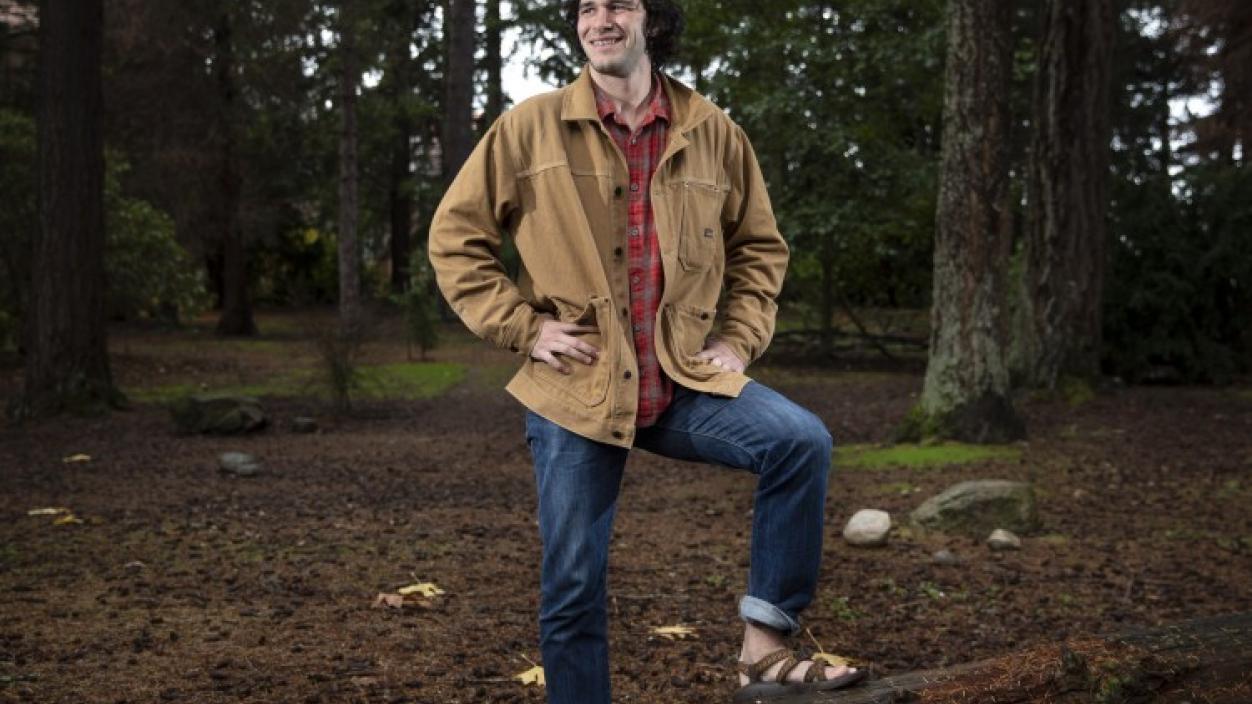 A person posing with one foot on a log