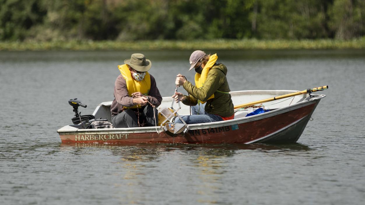 Two people using equipment in a boat on a lake