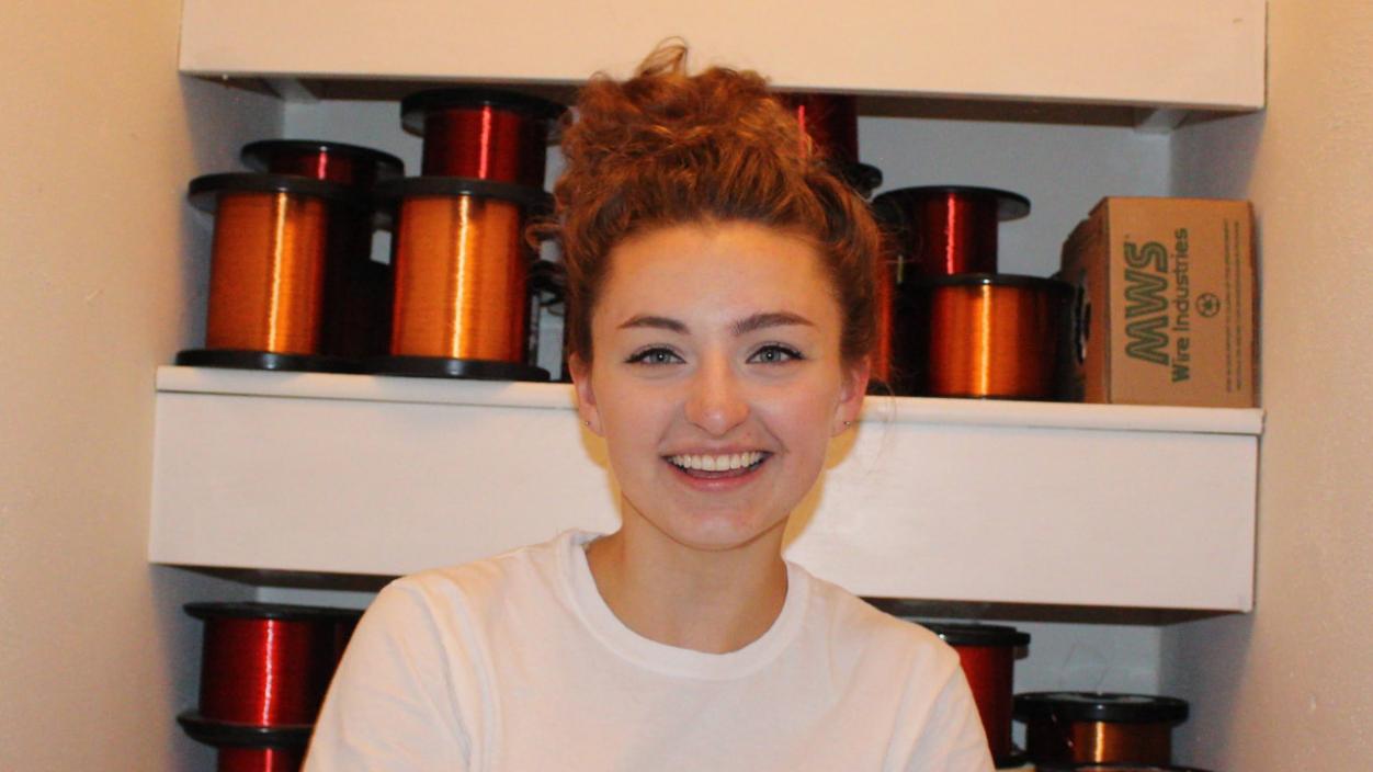 Emma McAllister standing in front of copper wire spools