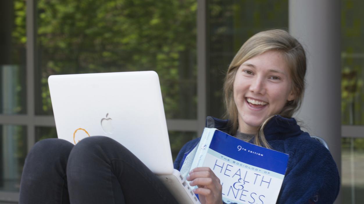A student sitting with a laptop in her lap