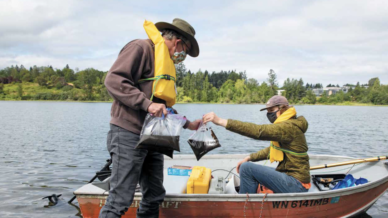 Two people on a boat holding water sample bags