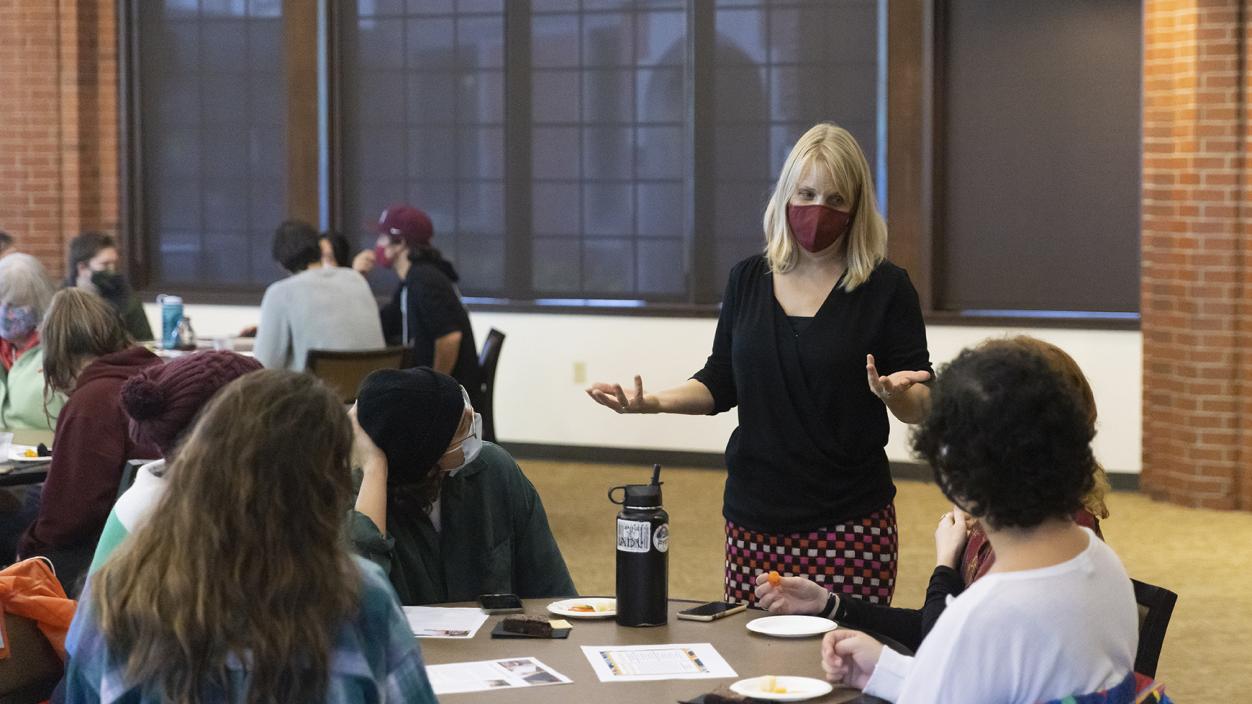 Prof. Tanya Erzen stands at a table of students during class in Rasmussen Rotunda