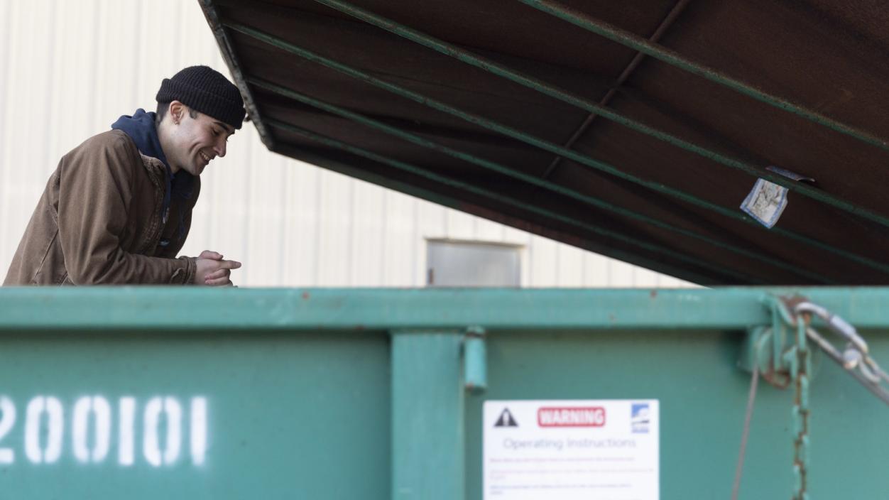 Alden Robert ’23 peers into a campus garbage container