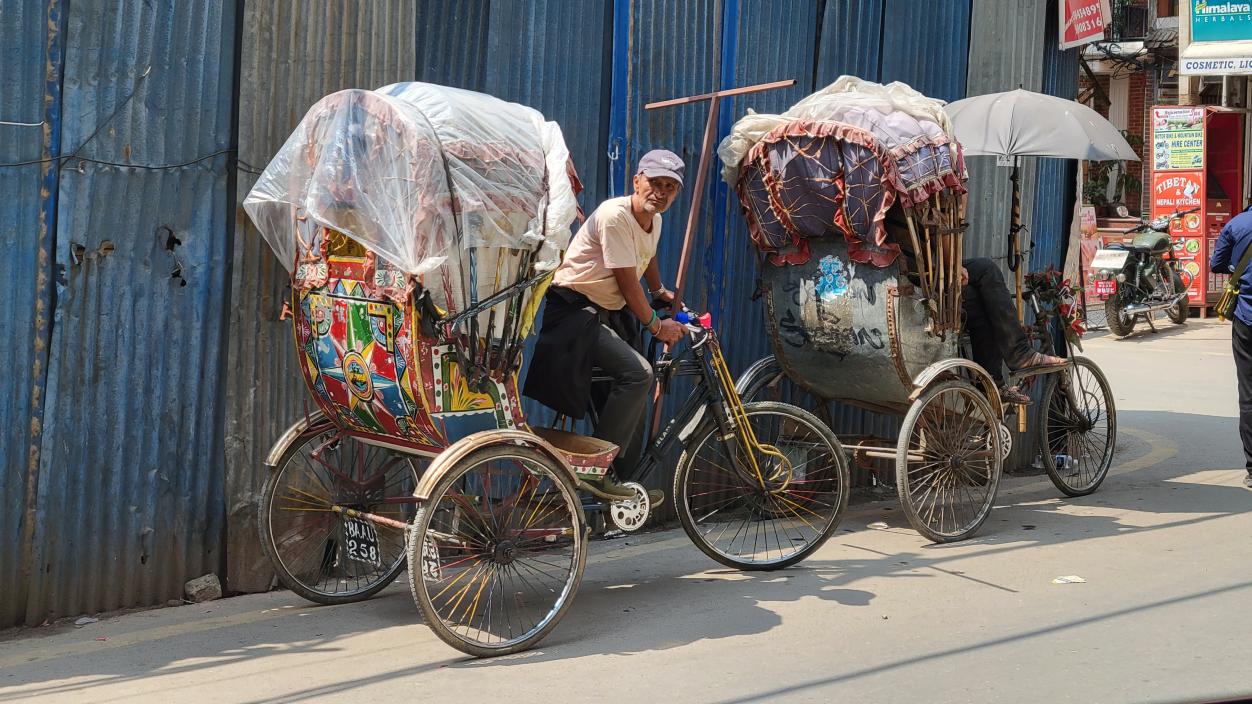 A man rides a heavily laden rickshaw.
