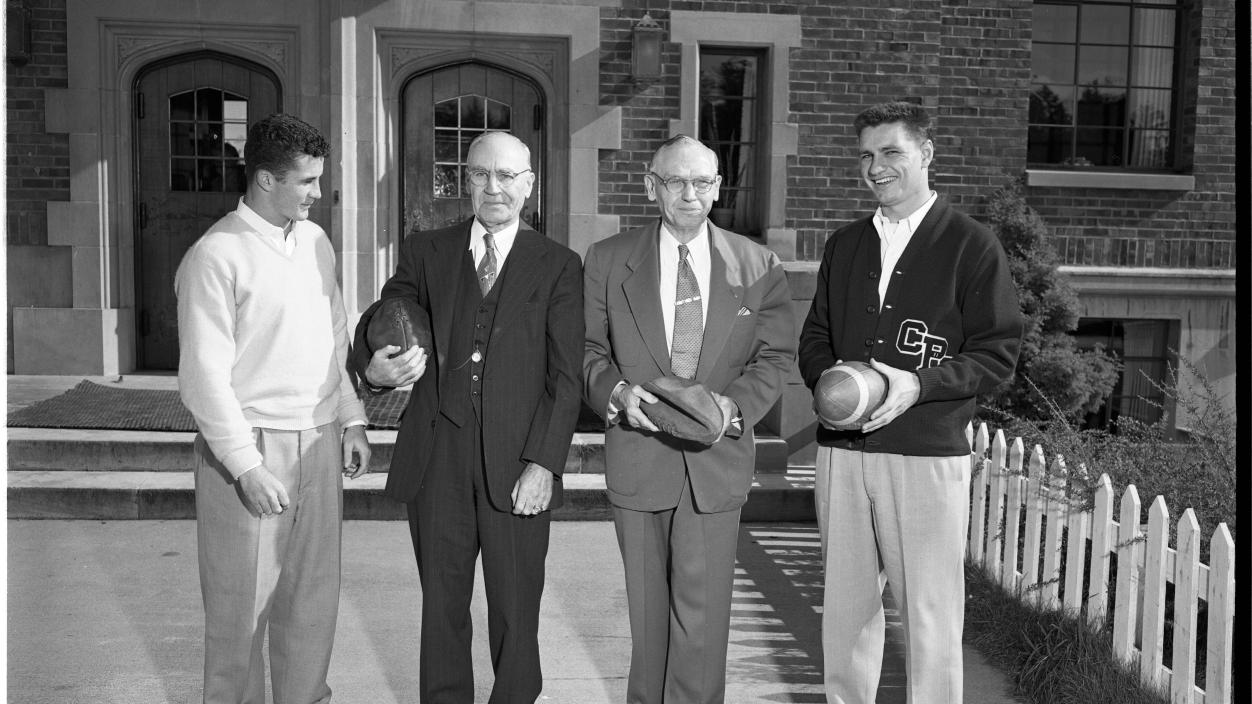 Sandy deCarteret, left, and Lou Grzadzielewski, right, quarterback and halfback respectively for the 1953 Logger football team, discuss football outside Todd Hall with members of the undefeated 1903 University of Puget Sound team, Raymond E. Cook, center left, and Dr. A George Nace.