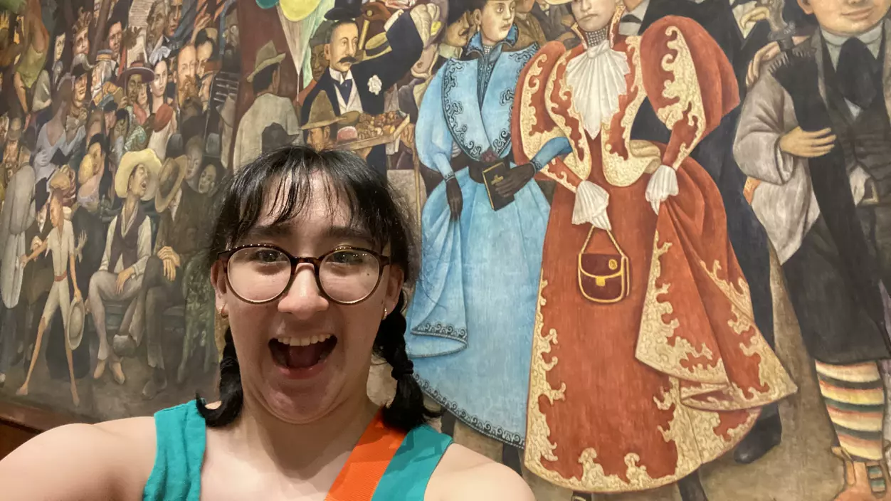Angela Ronces-Cortes ’24 in front a mural of faces in Mexico City.