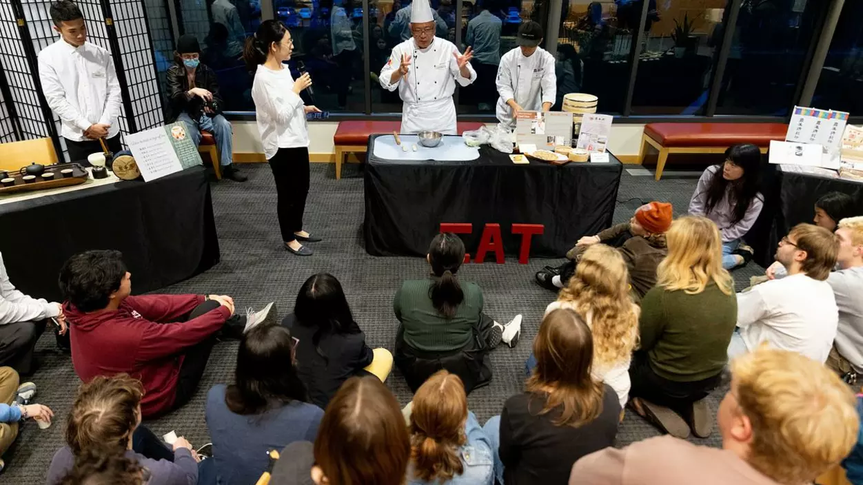 Chef Chou cooking Infront a college student audience. 
