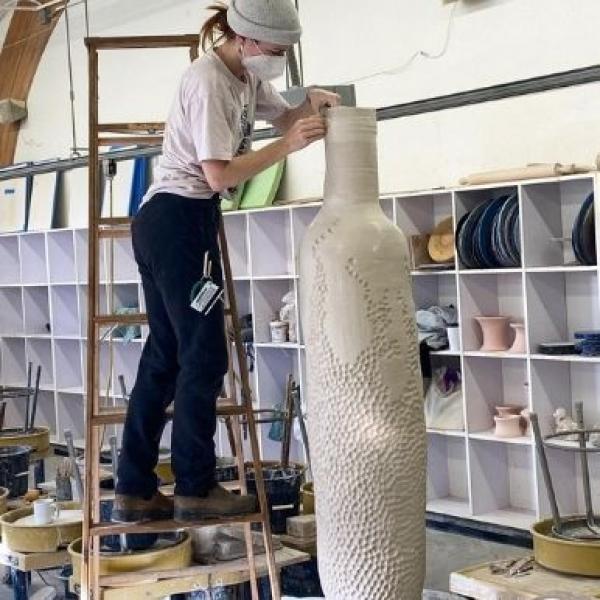 Student works on large clay pot in studio 