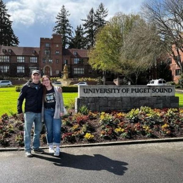 Two people pose in front of Puget Sound sign in Jones Circle