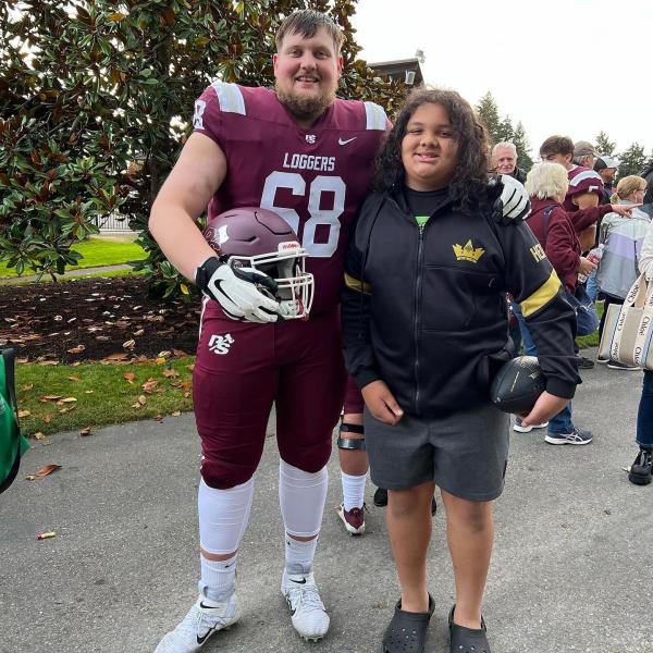 Logger football player stands next to his young guest