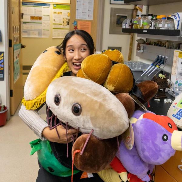 A student surrounded by microbial plushies
