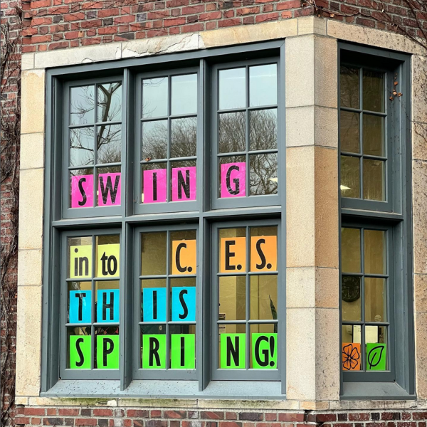 Colorful sheets of paper posted in the windows of Howarth Hall spell out "Swing in to CES this spring!"