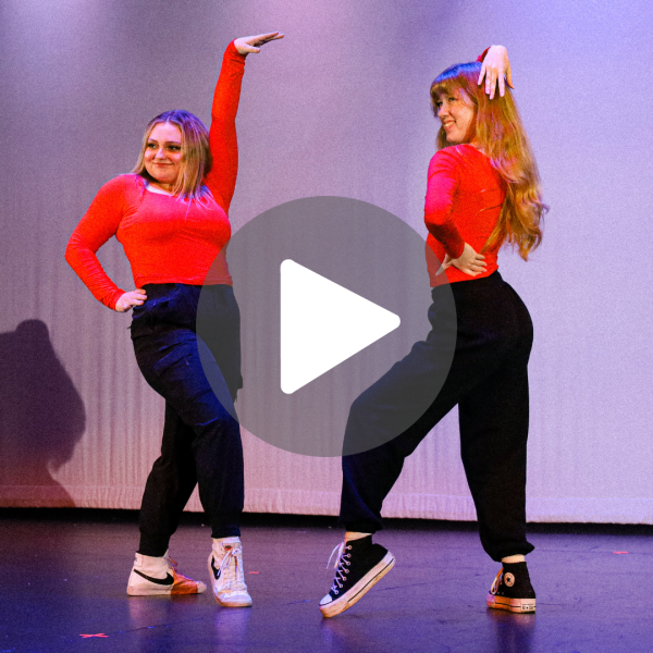 Two dancers in red shirts and black pants pose during the Fall Repertory Dance Group performance.