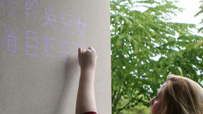 Students from Chinese 305 Chinese Poetry chalk poems in the courtyard of Wyatt Hall.