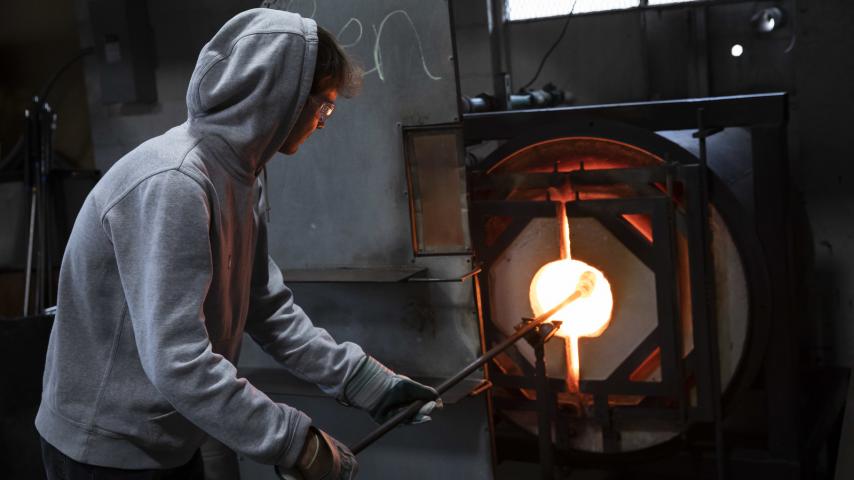 A person using a glass blowing furnace