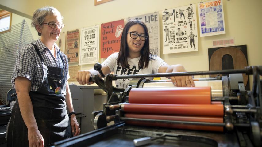 Two people using a letterpress printer