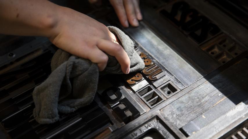 A person using a rag to clean metal letters