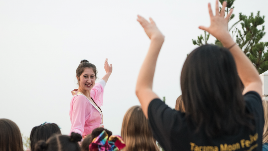 A person in a pink dress waving at a crowd of people