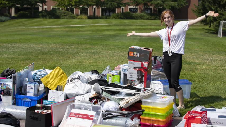 Moving in: student stands with piles of stuff to move into the residence halls