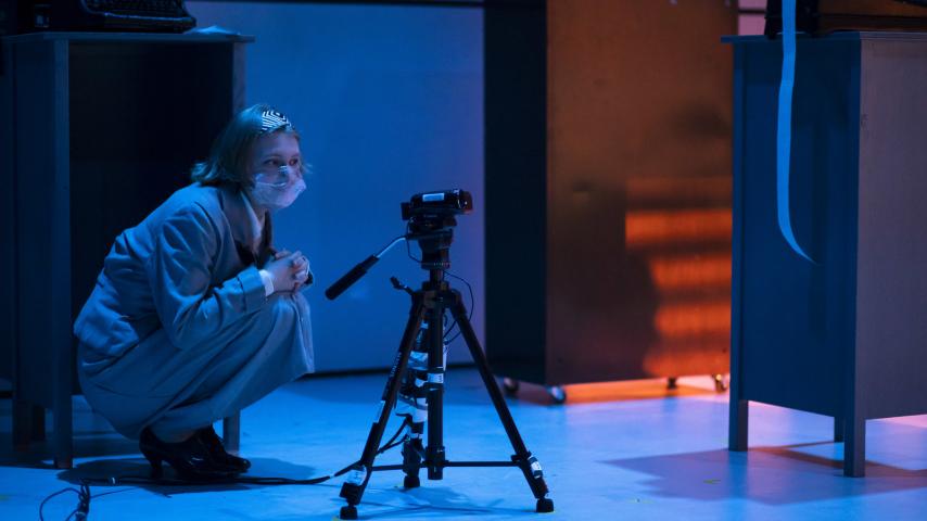 A student watches a streaming camera during a rehearsal of Machinal