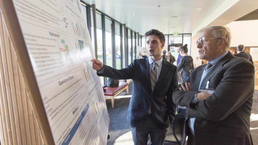 A person explaining a research board to another person