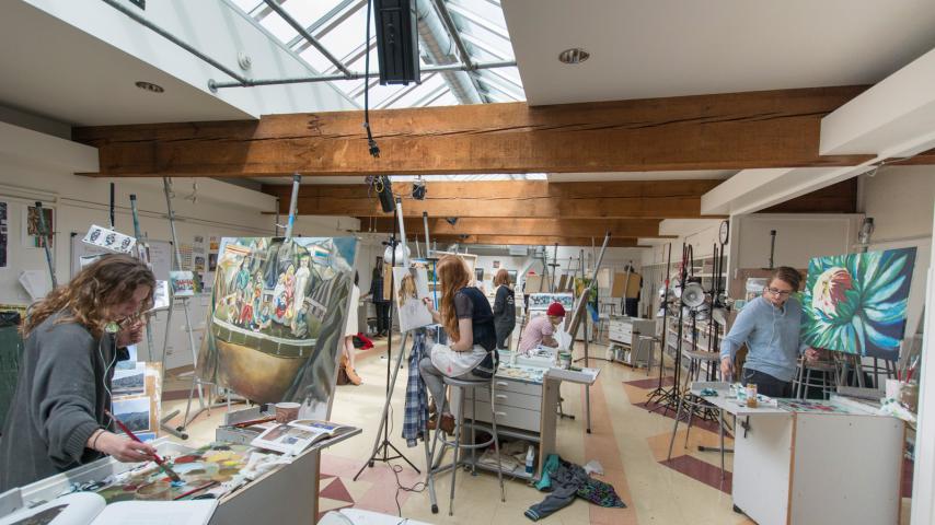 Students painting art in a studio workspace