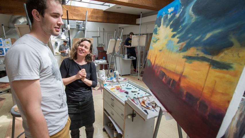Student and professor looking at a painting in the studio