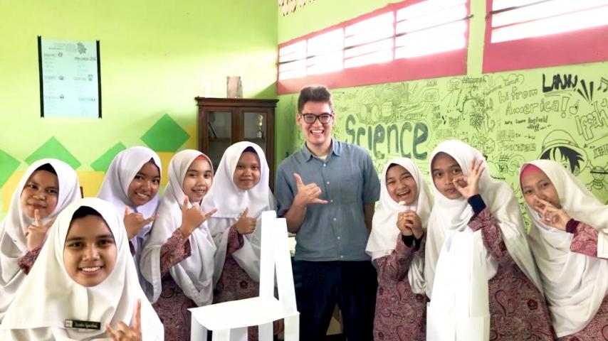Nicholas Navin in a classroom with a group of students in school uniform
