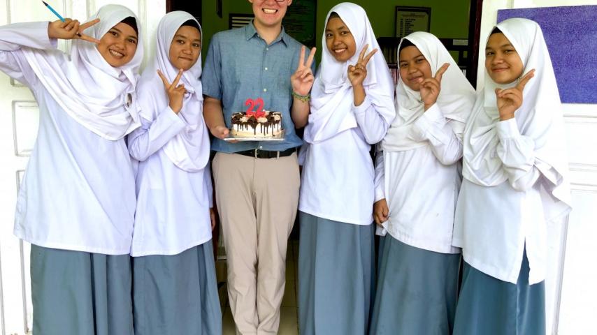 Nicholas Navin holding a birthday cake surrounded by students in school uniform