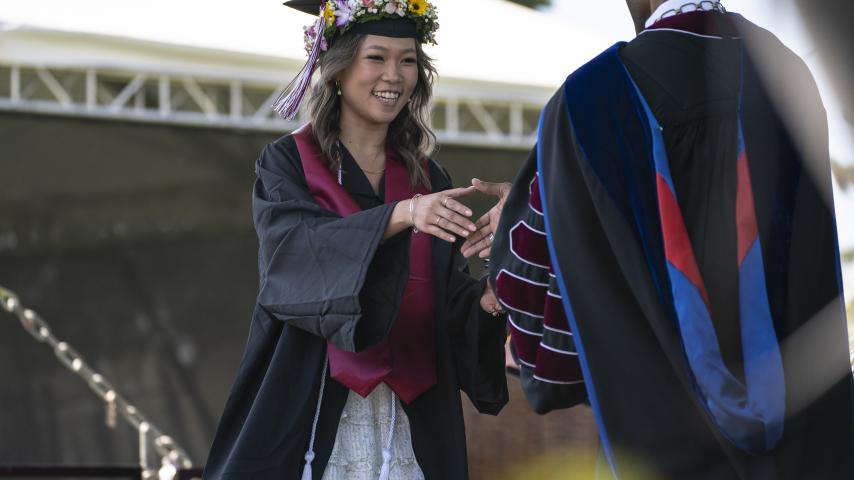 President Crawford congratulates a 2023 graduate as she receives her diploma.