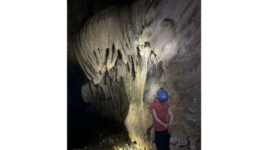Student looks at a stalactite in a limestone cave in Costa Rica. Georney trip 2023.