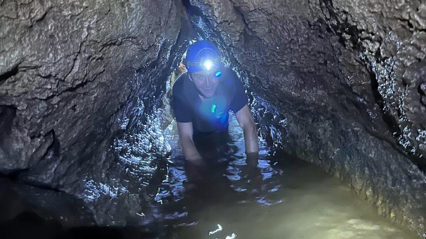 A Georneys student climbs through a narrow cave passage in Costa Rica, 2023.