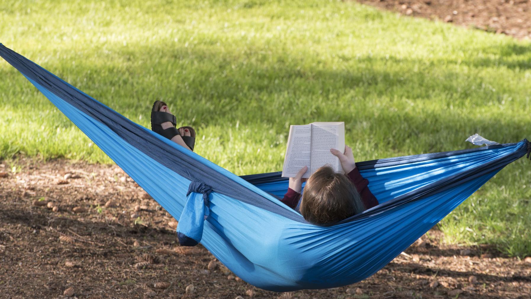 A student reads in a hammock on campus.