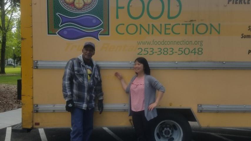 Two people standing in front of a truck.