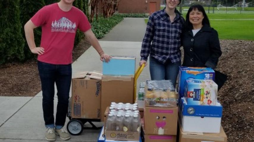 Three people standing in front of some boxes.