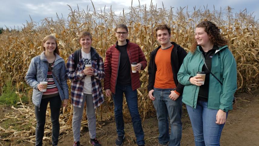 Five people standing in front of a corn field.