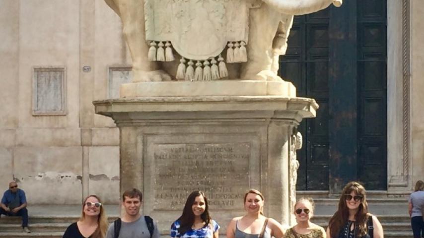 Six people standing in front of a statue.
