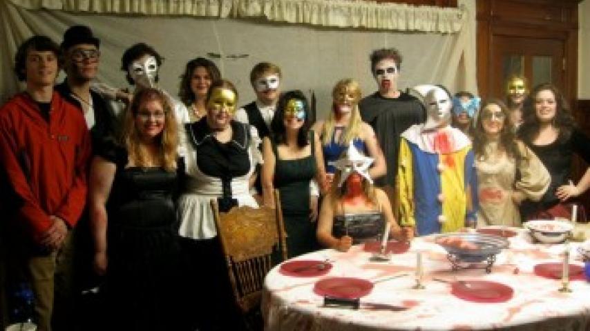 A group of people wearing costumes standing together in front of a table.
