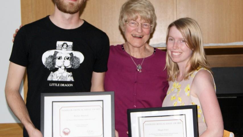Three people smiling with two awards.