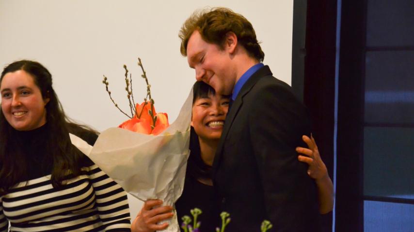 A person holding a bouquet of flowers and hugging another person.