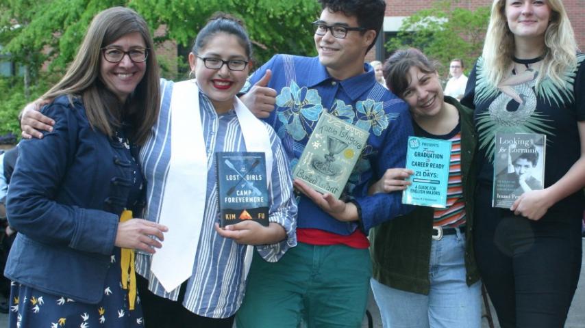 Five people smiling and holding books.
