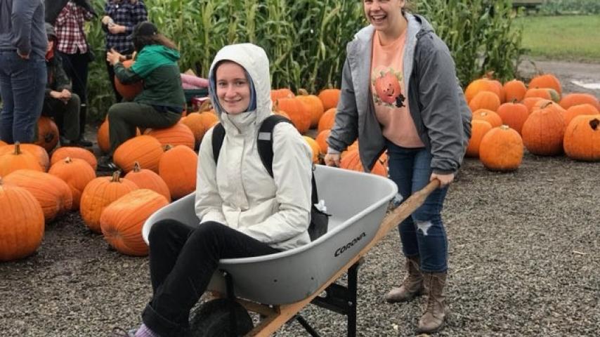 A person moving another person in a wheelbarrow.