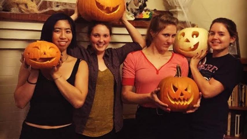 Four people holding carved pumpkins.