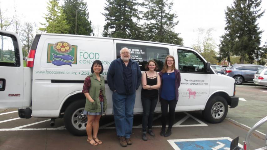Four people standing in front of a van.