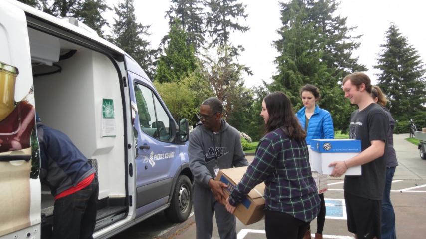 Five people moving some boxes into a van.