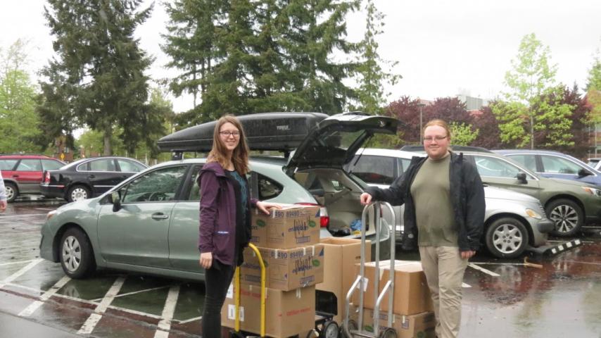 Two people standing next to some boxes in front of a car.