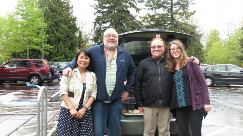 Four people standing in front of a car.