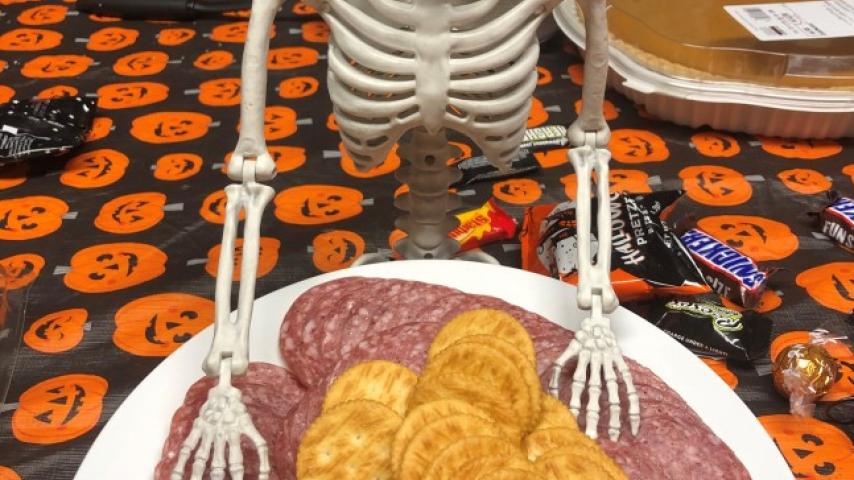 A skeleton figurine with a plate of food.
